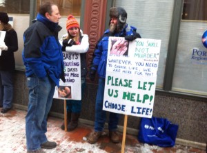 A man holds a pro-life sign to offer help to women during the protest.