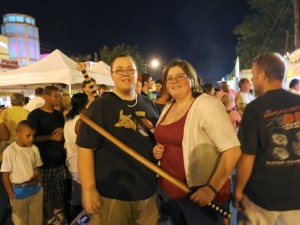 Festival-goers hold wooden swords sold by an event vendor.